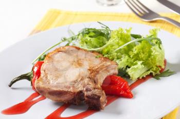 Roast pork chop and red pepper garnished with salad greens