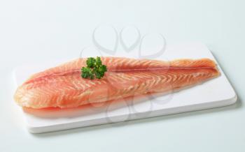 Raw fish fillet on cutting board