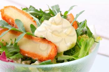 Green salad with fried cheese and salad dressing