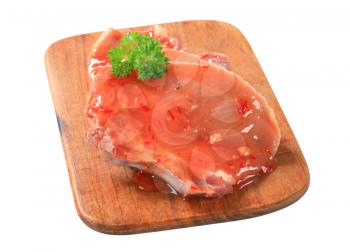 Raw pork chop brushed with spicy glaze