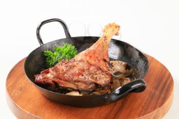 Roast duck leg and onion in a skillet
