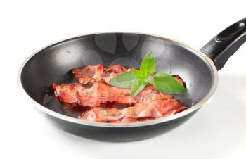 Strips of fried bacon on frying pan