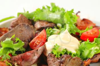 Pan fried chicken livers with salad greens and bacon strips