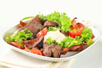 Pan fried chicken livers with salad greens and bacon strips
