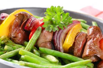 Liver skewer with green beans in a frying pan