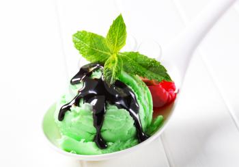 Green ice cream with chocolate syrup on a spoon