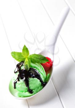 Green ice cream with chocolate syrup on a spoon