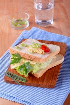 Cheese and lettuce sandwich on a cutting board