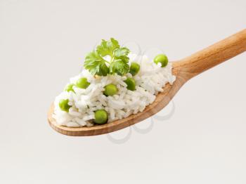 Rice and peas on a wooden spoon