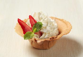 Whipped cream with strawberry in a wafer cup