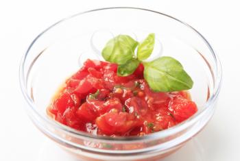 Bowl of peeled tomatoes with vinaigrette and basil 
