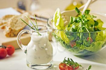 Bowl of greens and a jug of salad dressing