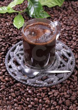 Glass of black coffee on a bed of coffee beans