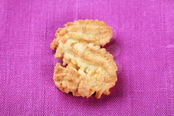 Single S-shaped Spritz cookie on purple background