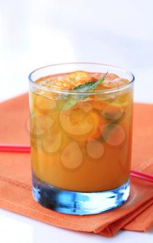 Glass of iced drink with slices of kumquat fruit
