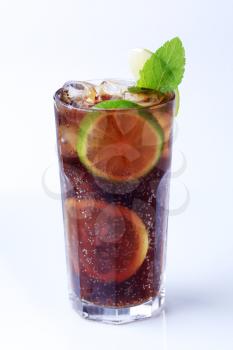 Tall glass of iced drink with slices of lime 