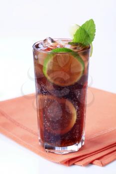 Tall glass of iced drink with slices of lime 