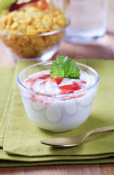Bowl of yogurt with fruit jelly, corn flakes in the background