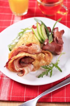 Fried egg omelet with bacon and sausages
