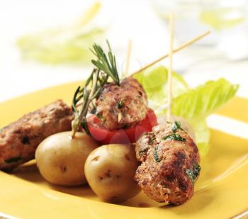 Minced meat kebabs on sticks and new potatoes