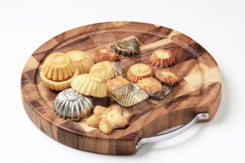 Small tart shells and baking pans on a cutting board