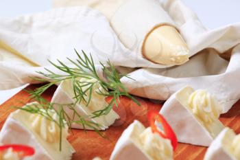 Pieces of white rind cheese garnished with dill and pepper