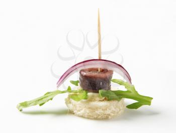 Anchovy canape garnished with arugula and onion