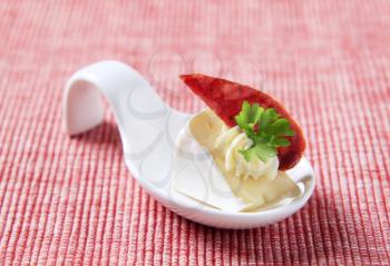 Soft white cheese with salami  on a porcelain spoon