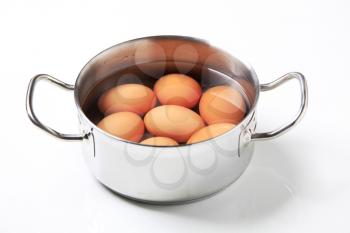Brown shelled eggs in water in a saucepan