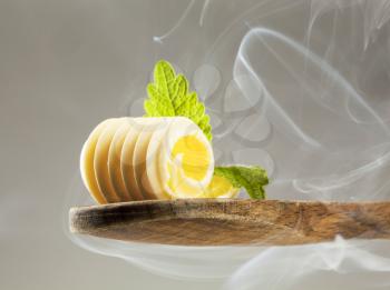 Butter curl on a wooden spoon in steam
