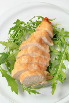 Sliced chicken breast fillet on a nest of salad greens