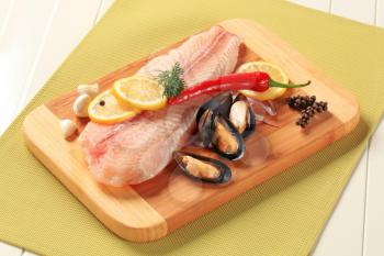 Fresh fish fillet and mussels on a cutting board