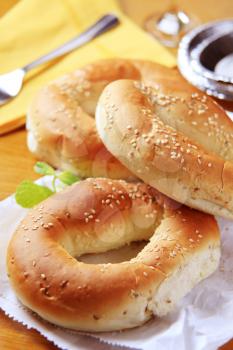 Three sesame seed bagels on a paper bag