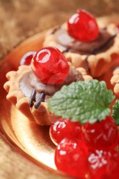 Chocolate filled tartlets topped with maraschino cherries