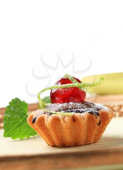 Chocolate filled tartlet topped with maraschino cherries