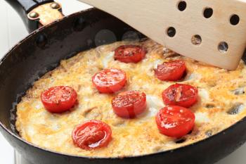 Egg omelet and cherry tomatoes in a frying pan