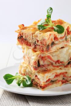 Three portions of lasagne stacked on a plate