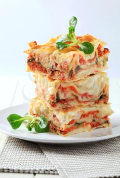 Three portions of lasagne stacked on a plate