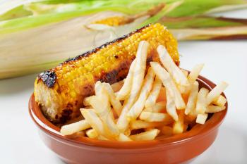 Grilled corn on the cob with French fries 