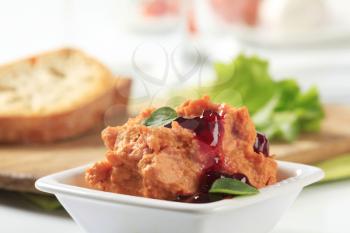 Small dish of spicy spread topped with cranberry sauce 