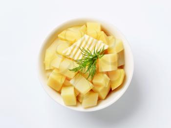 Bowl of diced potatoes topped with butter