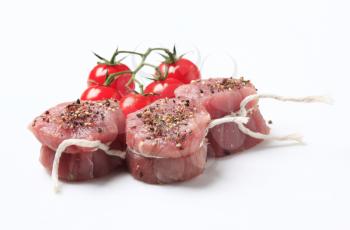 Raw pork filet mignons and red tomatoes