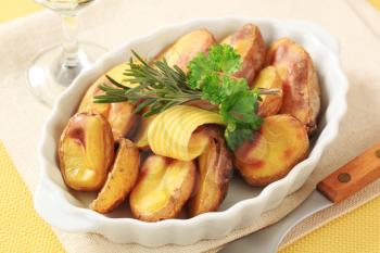 Halves of roasted unpeeled potatoes in a casserole dish