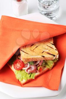 Calamari sandwich in orange napkin on a plate
