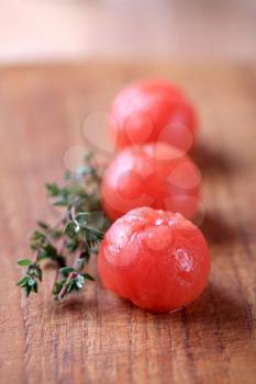 Peeled cherry tomatoes and a sprig of fresh thyme