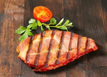 Grilled pork steak on dark brown wood
