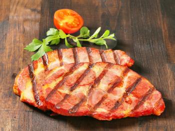 Grilled pork steaks on dark brown wood