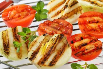 Grilled tomatoes and onions on barbecue grid