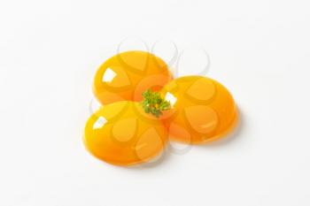 Three raw egg yolks on white background