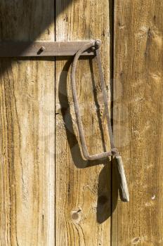 Rusty handsaw hanging on wooden gate